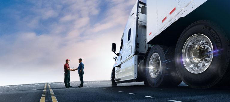 An image of two men shaking hands on a road next to an eighteen-wheeler